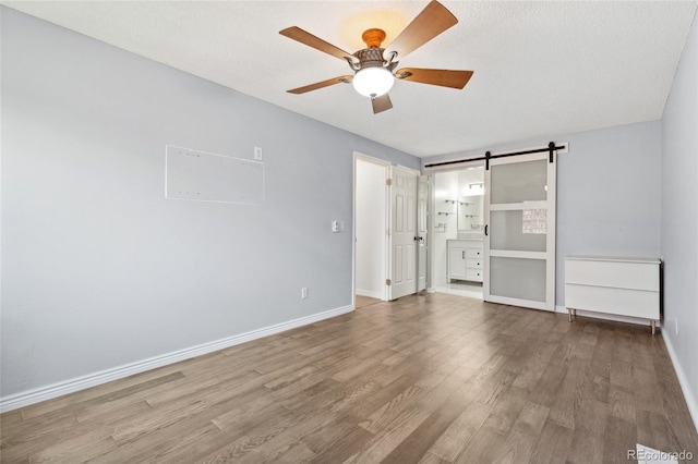 4860 S Field Way, Littleton, CO 80123 - empty room featuring a ceiling fan, a barn door, and wood finished floors