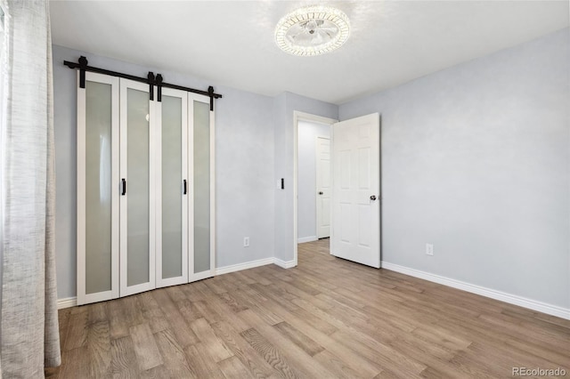 4860 S Field Way, Littleton, CO 80123 - unfurnished bedroom featuring wood finished floors and a barn door
