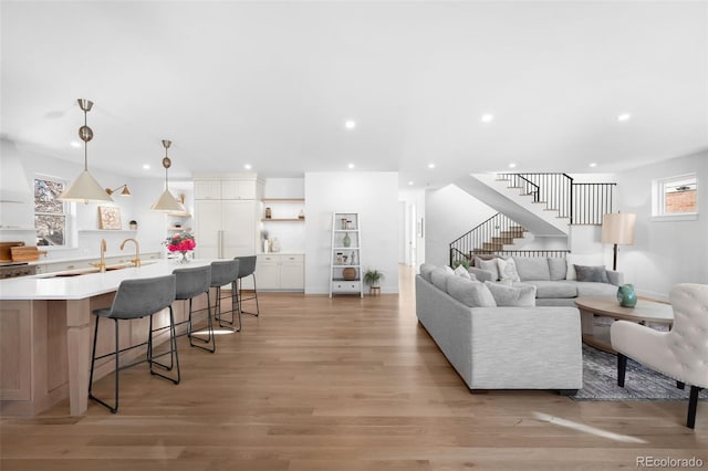 living room featuring a wealth of natural light, sink, and light wood-type flooring