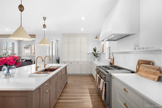 kitchen featuring white cabinetry, sink, premium range hood, double oven range, and decorative light fixtures