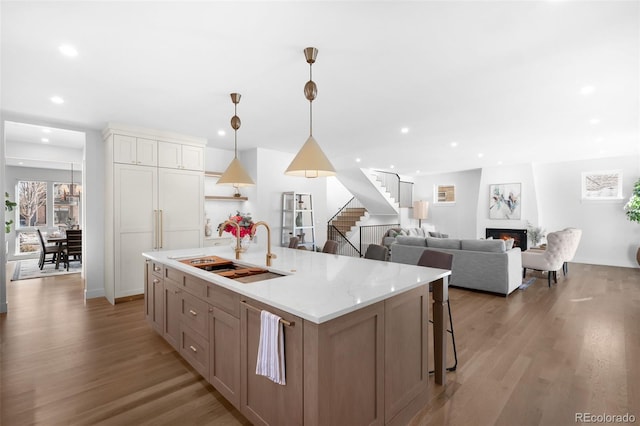 kitchen with sink, pendant lighting, white cabinets, light hardwood / wood-style floors, and a large island