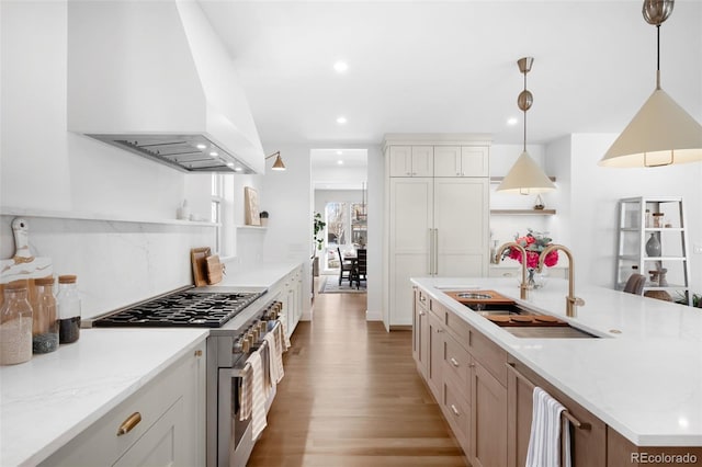 kitchen with pendant lighting, double oven range, sink, custom range hood, and white cabinetry