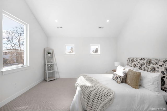 bedroom with lofted ceiling, light carpet, and multiple windows