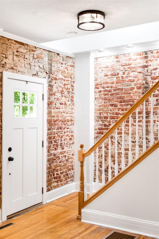 3375 W 37th Ave, Denver, CO 80211 - foyer entrance with brick wall, baseboards, light wood finished floors, crown molding, and stairway