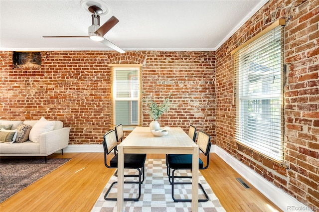3375 W 37th Ave, Denver, CO 80211 - dining room featuring brick wall, baseboards, ornamental molding, wood finished floors, and a ceiling fan