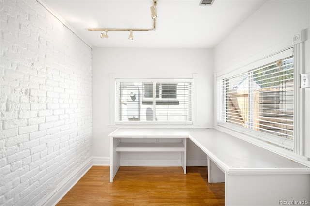 3375 W 37th Ave, Denver, CO 80211 - unfurnished dining area with brick wall, rail lighting, wood finished floors, and baseboards