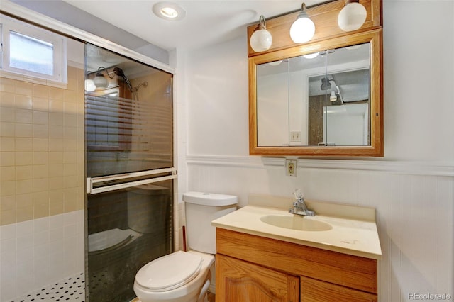 bathroom with vanity, toilet, and a shower with door