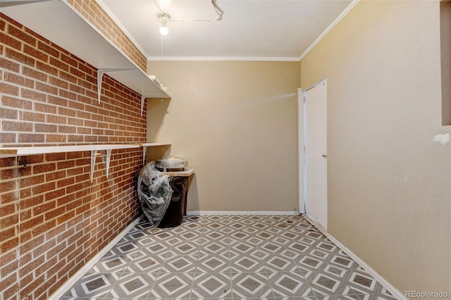 clothes washing area featuring ornamental molding and brick wall