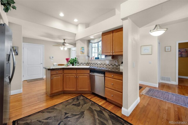 4529 Songglen Cir, Colorado Springs, CO 80906 - kitchen featuring stainless steel appliances, light wood-type flooring, a peninsula, decorative backsplash, and ceiling fan