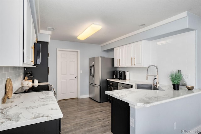 kitchen with stainless steel appliances, sink, white cabinetry, tasteful backsplash, and kitchen peninsula