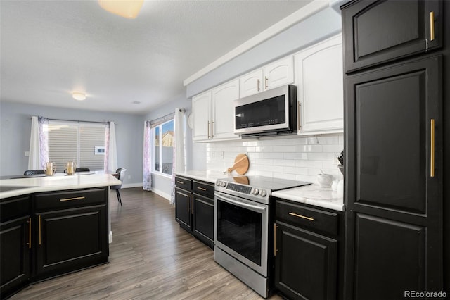 kitchen featuring light hardwood / wood-style flooring, stainless steel appliances, white cabinets, and decorative backsplash