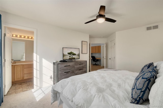 carpeted bedroom with ensuite bathroom and ceiling fan