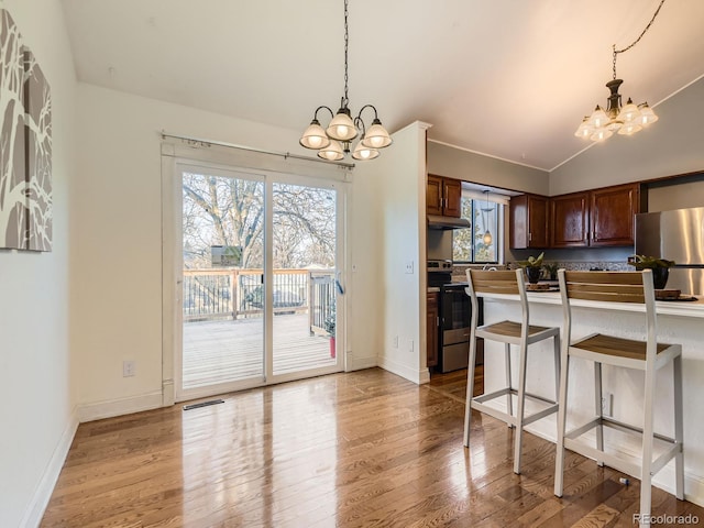 kitchen with hanging light fixtures, stainless steel appliances, a notable chandelier, and a breakfast bar