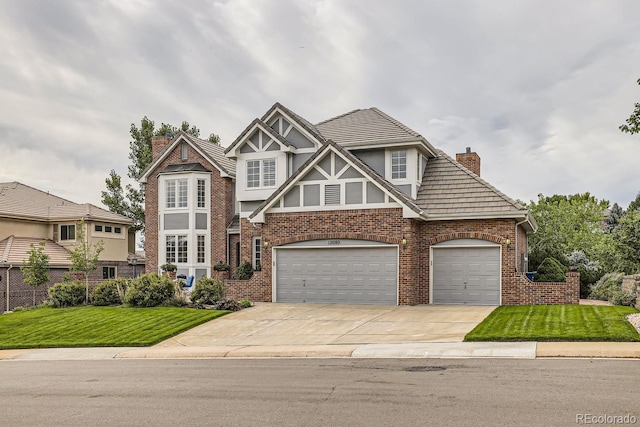 tudor-style house featuring a garage and a front yard