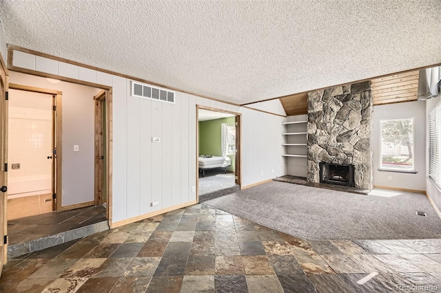 2469 S Xanadu Way Unit A, Aurora, CO 80014 - unfurnished living room with baseboards, stone tile flooring, a textured ceiling, a stone fireplace, and ornamental molding