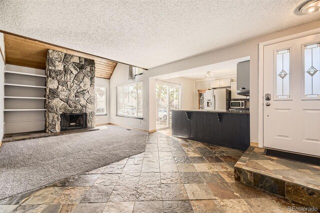 2469 S Xanadu Way Unit A, Aurora, CO 80014 - living area with stone tile flooring, baseboards, a textured ceiling, a stone fireplace, and lofted ceiling