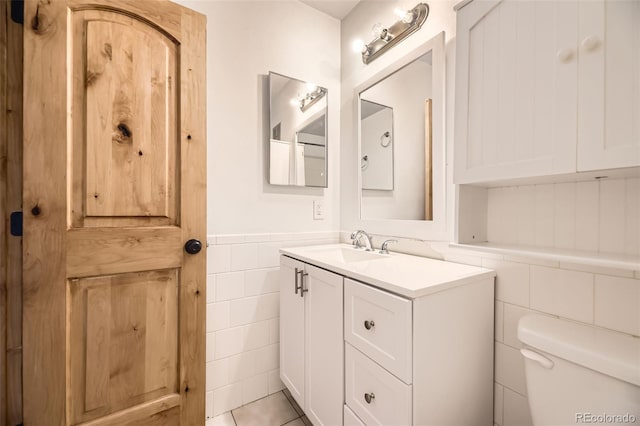 2469 S Xanadu Way Unit A, Aurora, CO 80014 - bathroom featuring tile walls, toilet, wainscoting, and vanity