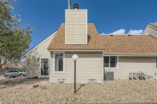 2469 S Xanadu Way Unit A, Aurora, CO 80014 - rear view of property with a shingled roof, central AC unit, and a chimney