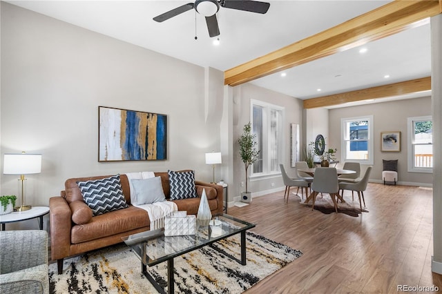 living room featuring ceiling fan, hardwood / wood-style flooring, and beamed ceiling