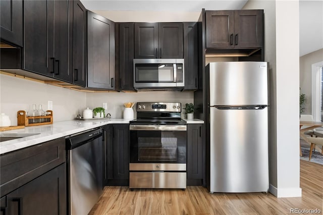 kitchen with dark brown cabinetry, stainless steel appliances, and light wood-type flooring