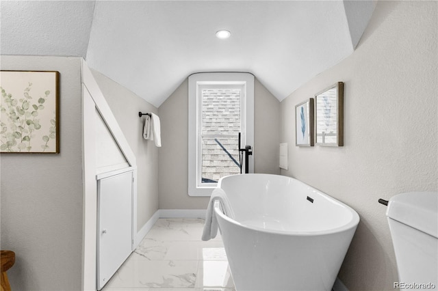 bathroom with lofted ceiling and a bath