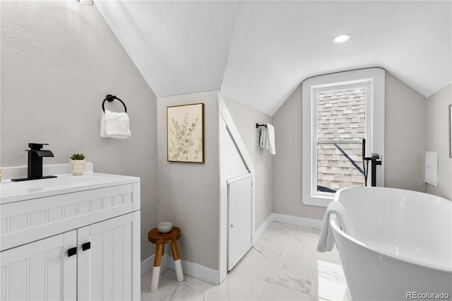 bathroom with lofted ceiling, a bath, and vanity