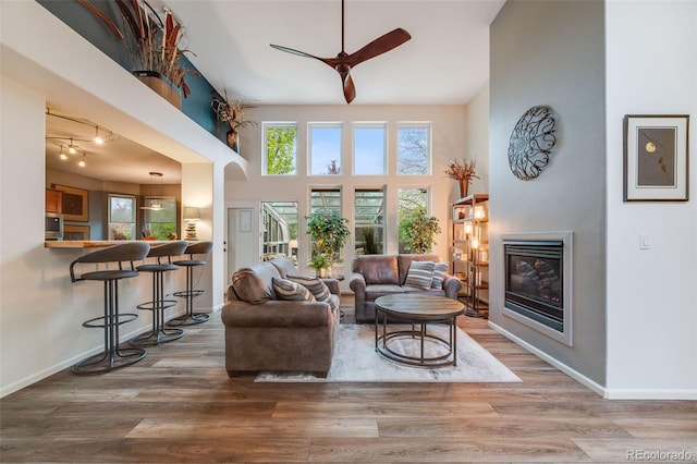 236 E Fair Ln, Centennial, CO 80121 - living area with a glass covered fireplace, wood finished floors, a ceiling fan, baseboards, and a towering ceiling