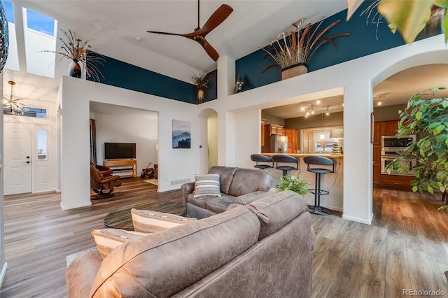 236 E Fair Ln, Centennial, CO 80121 - living area with arched walkways, high vaulted ceiling, ceiling fan, light wood finished floors, and baseboards
