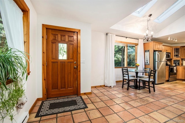 tiled entryway with a notable chandelier, lofted ceiling with skylight, and a healthy amount of sunlight