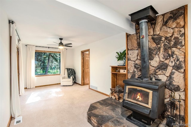 interior space with ceiling fan, carpet floors, and a wood stove