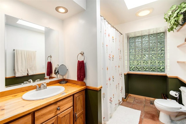 bathroom with a skylight, vanity, and toilet