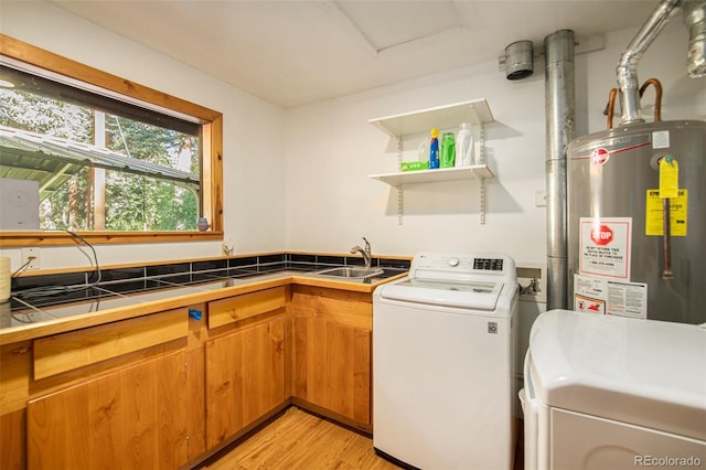 laundry area with sink, washer and clothes dryer, cabinets, gas water heater, and light wood-type flooring