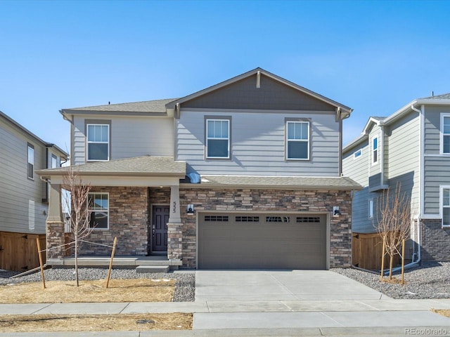 view of front facade with driveway, stone siding, fence, an attached garage, and a shingled roof