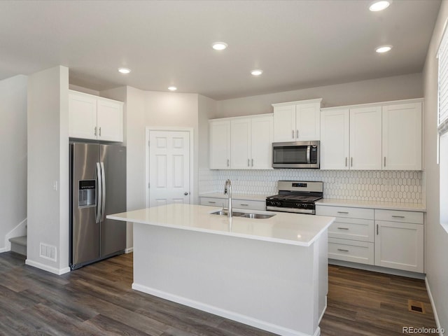 kitchen with dark wood finished floors, a sink, stainless steel appliances, white cabinetry, and backsplash