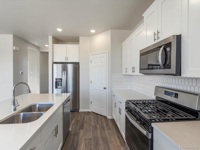 kitchen featuring dark wood-style floors, a sink, light countertops, appliances with stainless steel finishes, and backsplash