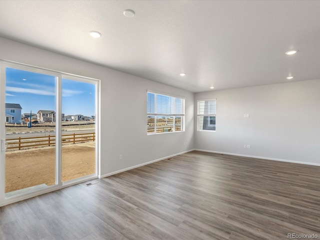 spare room with recessed lighting, wood finished floors, and baseboards