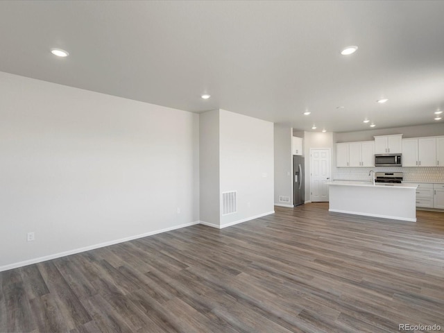 unfurnished living room with dark wood finished floors, recessed lighting, baseboards, and visible vents