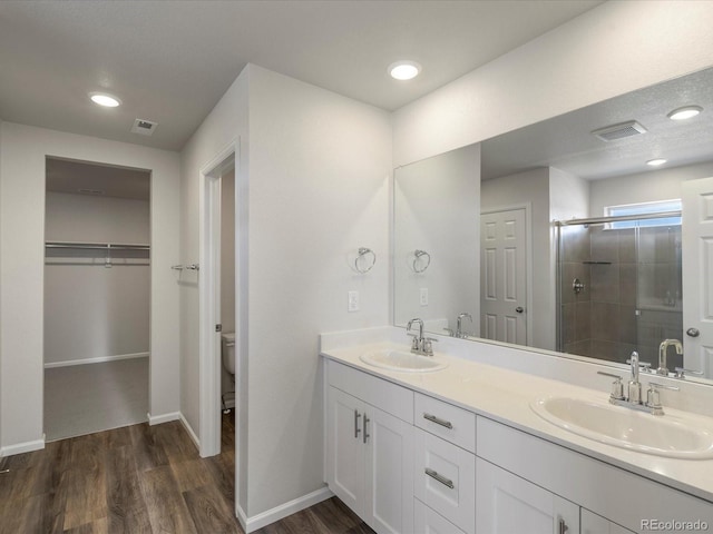 full bathroom with a shower stall, wood finished floors, toilet, and a sink