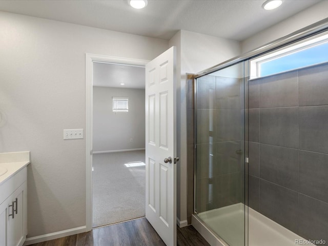 full bath featuring a wealth of natural light, vanity, wood finished floors, and a shower stall