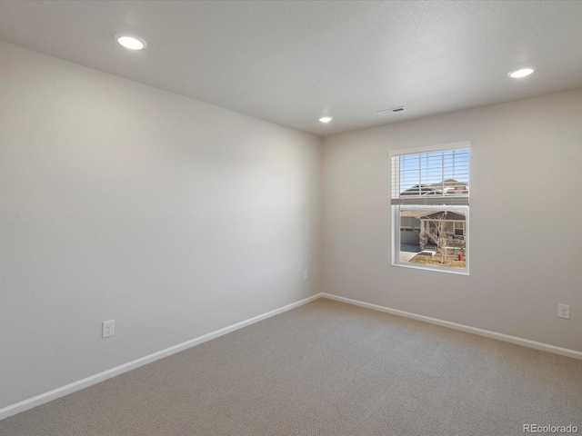 empty room featuring visible vents, light colored carpet, and baseboards