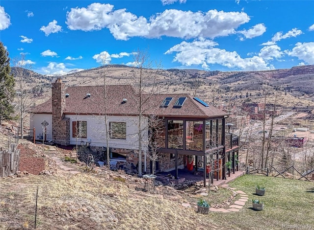 224 W Warren Ave, Cripple Creek, CO 80813 - rear view of house featuring a chimney, a mountain view, a patio area, and stone siding