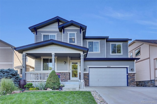 8489 S Quay St, Littleton, CO 80128 - craftsman-style house featuring a garage, a porch, concrete driveway, and stone siding