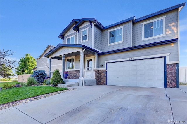 8489 S Quay St, Littleton, CO 80128 - craftsman house featuring stone siding, a garage, driveway, covered porch, and a front lawn