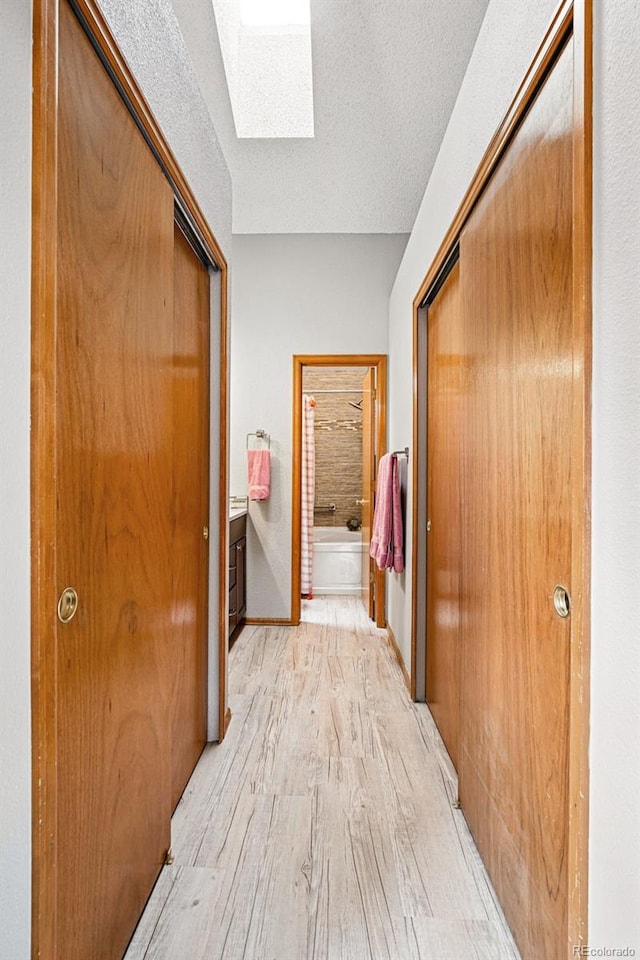 13313 Cherry Cir, Thornton, CO 80241 - corridor with light wood-type flooring, a skylight, and a textured ceiling