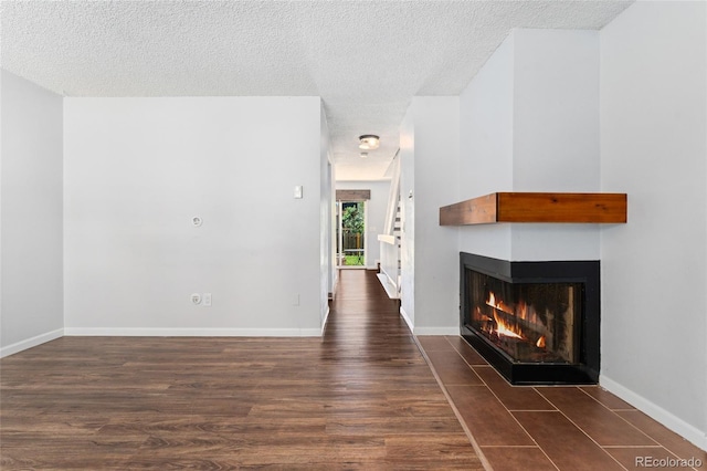 6011 Yarrow St Unit I, Arvada, CO 80004 - unfurnished living room featuring a multi sided fireplace, a textured ceiling, and wood finished floors