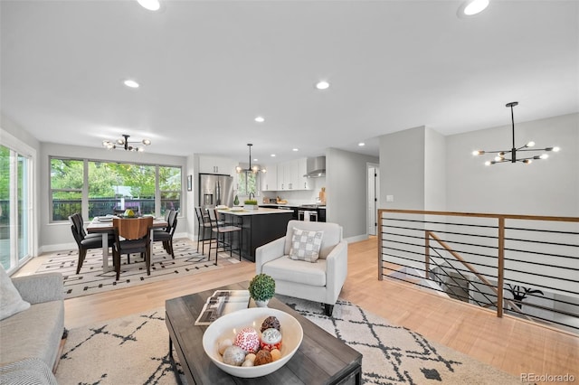 living area with a chandelier, light wood-type flooring, recessed lighting, and baseboards