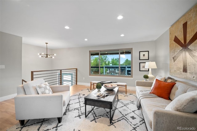 living area featuring a chandelier, baseboards, light wood-style flooring, and recessed lighting