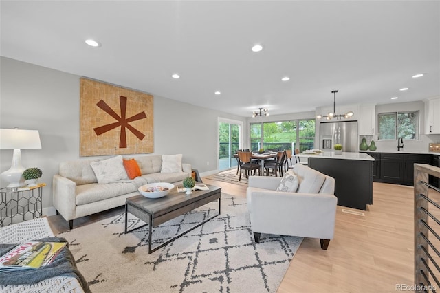 living room featuring a chandelier, recessed lighting, light wood-style flooring, and baseboards