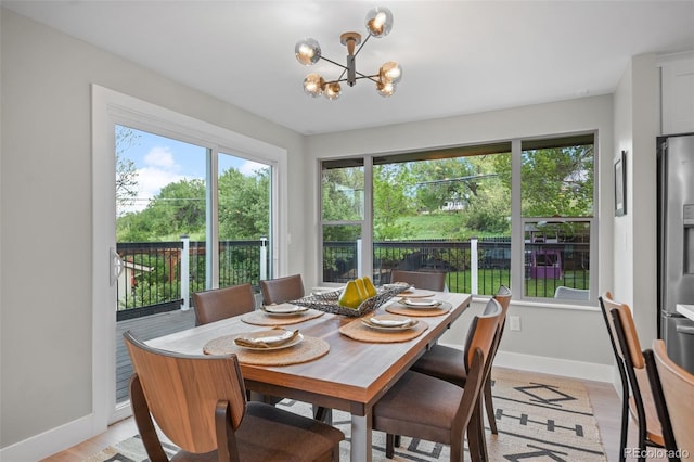 dining area featuring a chandelier, baseboards, plenty of natural light, and light wood-style flooring