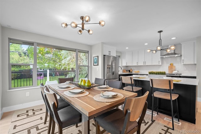 dining area with a chandelier, baseboards, and light wood-style floors